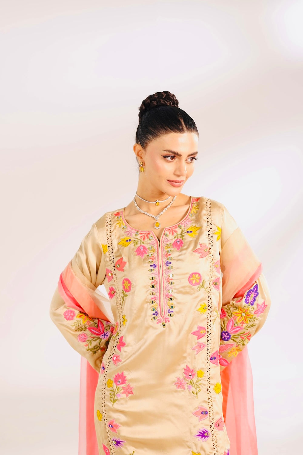Woman wearing a traditional embroidered outfit with a plain background