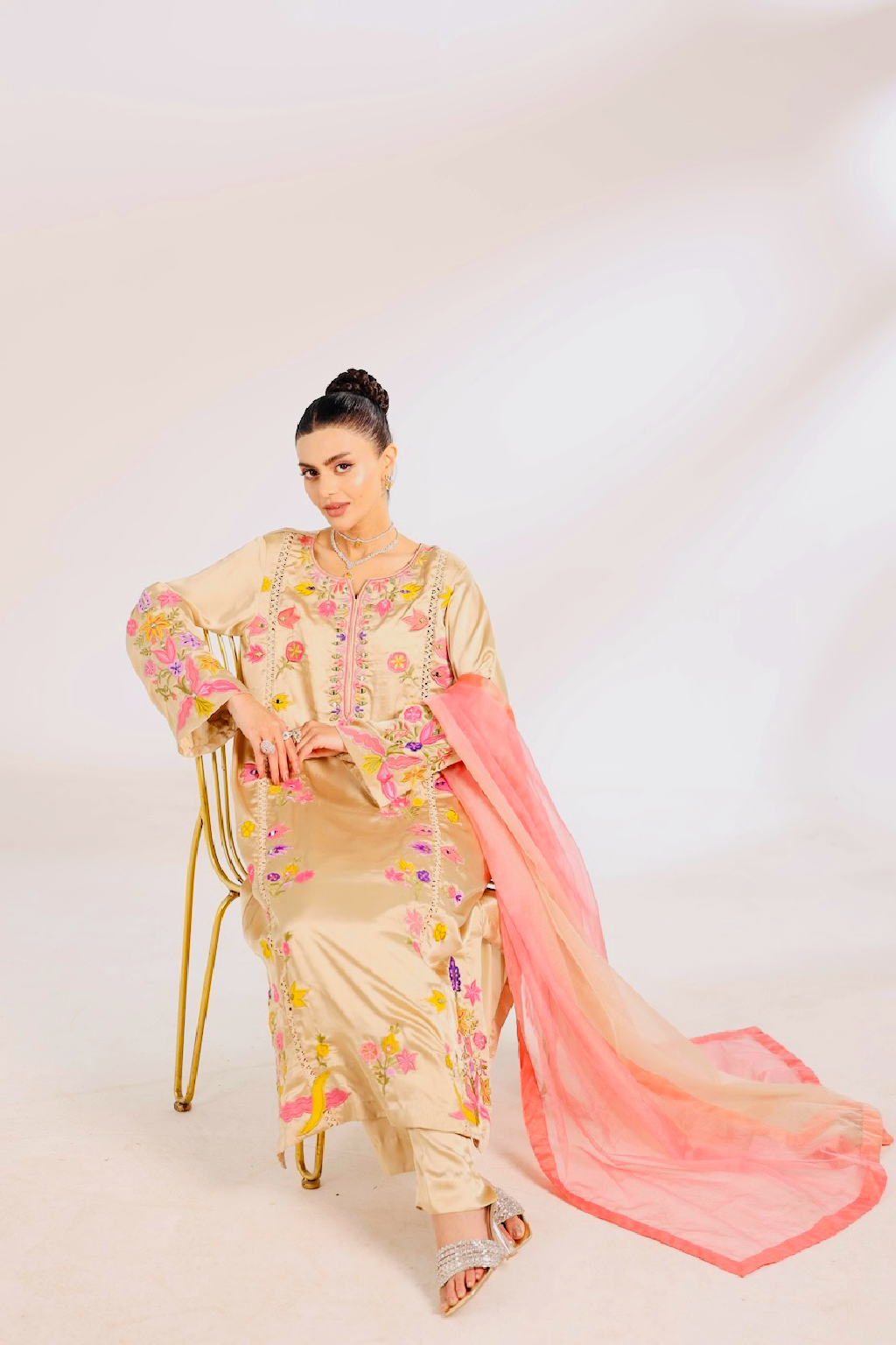 Woman in a traditional Pakistani raw silk outfit with floral patterns of patchwork 