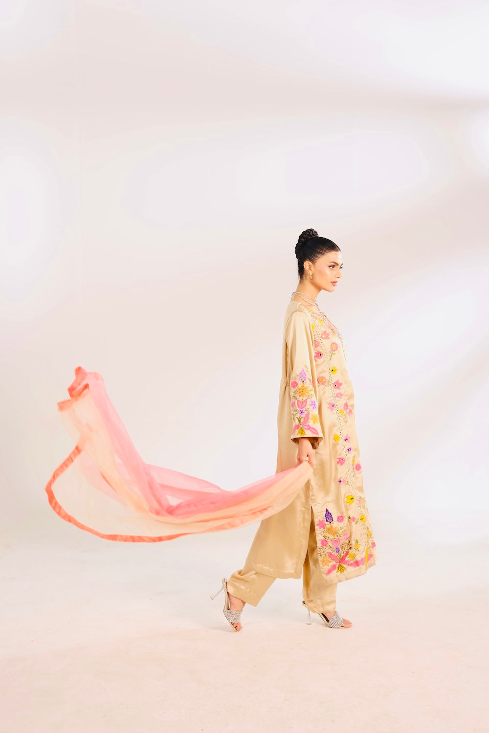 Woman in Pakistani Indian outfit with a flowing pink scarf on a white background