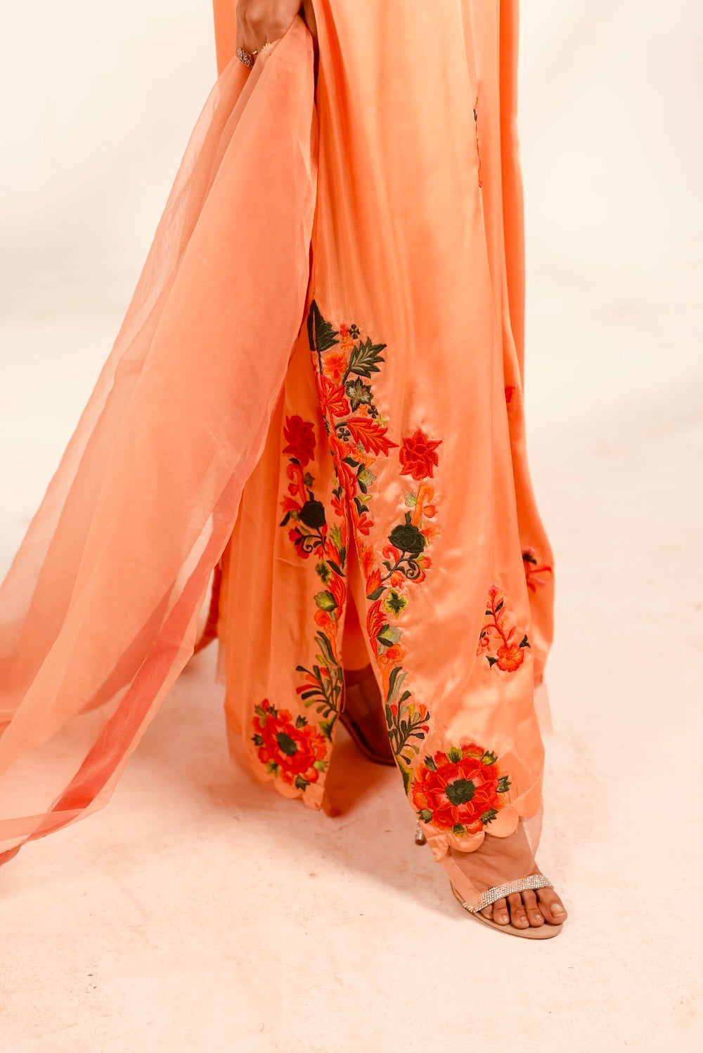 Peach-colored traditional outfit with floral embroidery on a white background